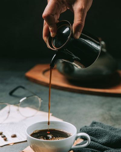 A close-up of a hand pouring coffee water into a coffee cup, int A close-up of a hand pouring coffee water into a coffee cup, international coffee day concept